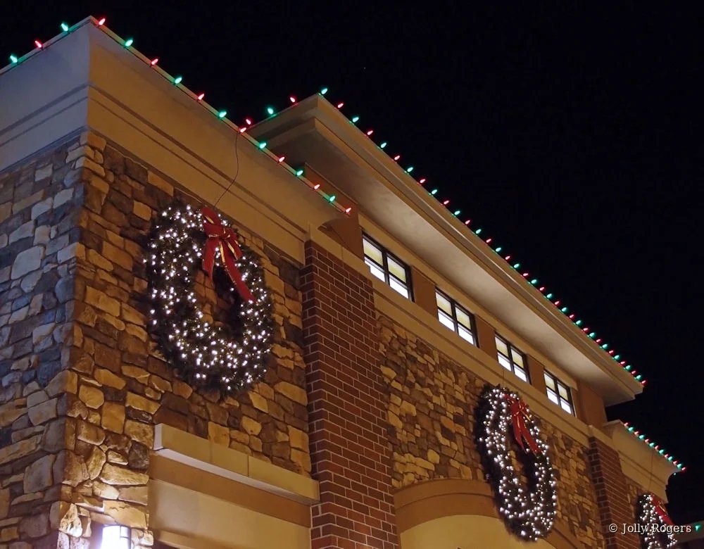 Commercial building wreaths and red green roofline lighting