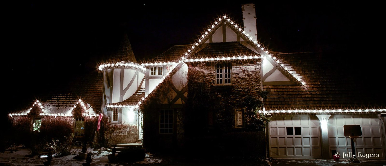 Tudor style home crisp white roofline Christmas lighting